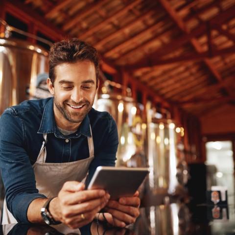 A mean uses a tablet inside a brewery